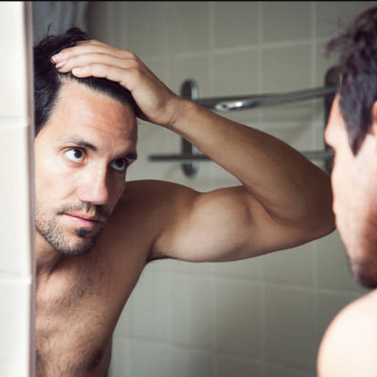 Close-up van een man die in de spiegel kijkt vanwege haaruitval bij mannen